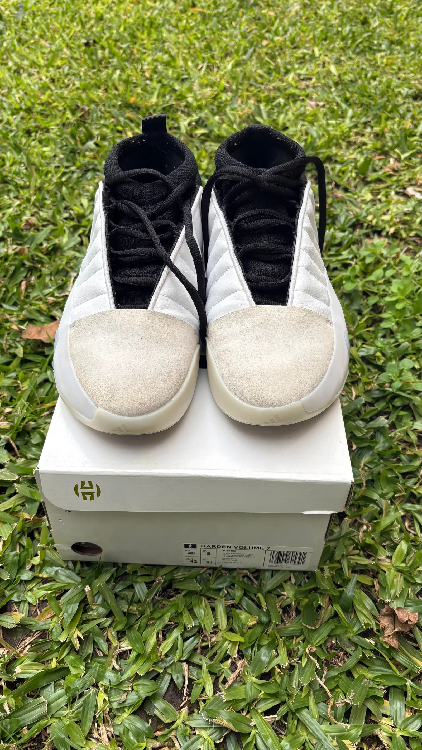 Par de Adidas Harden Volume 7 blancas y negras visto de frente sobre su caja