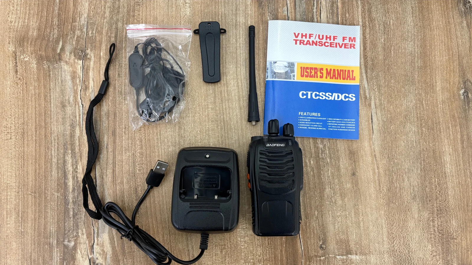 Un handy Baofeng BF-888S junto a su batería, antena, base de carga USB, clip, correa, auricular y manual